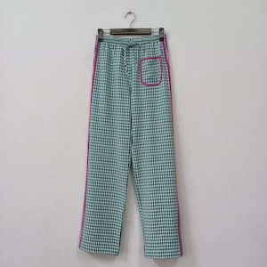 May include: Green and white checkered pants with pink piping along the sides. The pants have a drawstring waist and a single pocket on the right side.