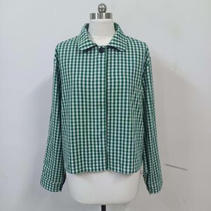 May include: A green and white gingham-patterned jacket with long sleeves and a collar. The jacket has a single black button closure and is displayed on a mannequin. The fabric has a classic checkered design, offering a casual yet stylish look.