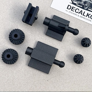 Peut inclure: Un ensemble de pièces de voiture en plastique noir, comprenant deux petits engrenages, deux petites pièces rondes et deux pièces plus grandes avec un bouton rond à une extrémité. Les pièces plus grandes sont probablement pour le mécanisme de la fenêtre d'une voiture.