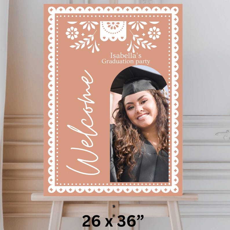 May include: A peach-colored welcome sign with a white decorative border and a cutout for a photo. The sign says "Isabella's Graduation Party" and "Welcome" in white script. The sign is 26 inches by 36 inches.