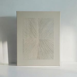 Könnte beinhalten: Ein weißes Leinwand-Wandbild mit einem erhabenen, strukturierten Design, das einem Sternenausbruch ähnelt.