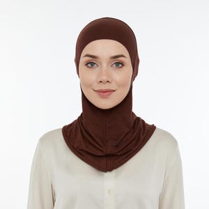 May include: A brown jersey knit hijab with a long neck covering. The hijab is made of a soft, stretchy fabric.