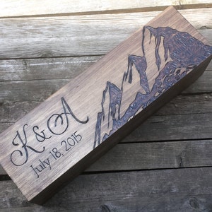 May include: A wooden box with a mountain range design and the text "K&A July 18, 2015" engraved on the front.