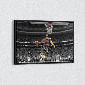 Könnte beinhalten: Gerahmtes Schwarz-Weiß-Foto eines Basketballspielers im Sprung, kurz davor, den Ball zu dunken. Der Spieler trägt ein Trikot mit der Nummer 23. Der Hintergrund ist eine überfüllte Basketballarena.