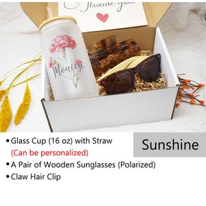 May include: A white gift box containing a personalised glass cup with a straw, a pair of wooden sunglasses, and a brown claw hair clip. The box is labelled "Sunshine".