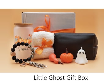May include: A gift box filled with Halloween themed items, including a black and white ghost candle, a white towel with an orange ribbon, a black beaded bracelet with the name "Jessica" on it, a pumpkin-themed tumbler, and a small orange pumpkin.