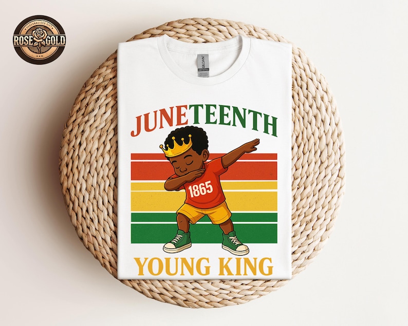 Puede incluir: Camiseta blanca con una ilustraci&oacute;n de dibujos animados de un ni&ntilde;o negro joven haciendo dab, con una corona y el n&uacute;mero 1865. La camiseta tiene las palabras "Juneteenth" y "Young King" en un dise&ntilde;o colorido.