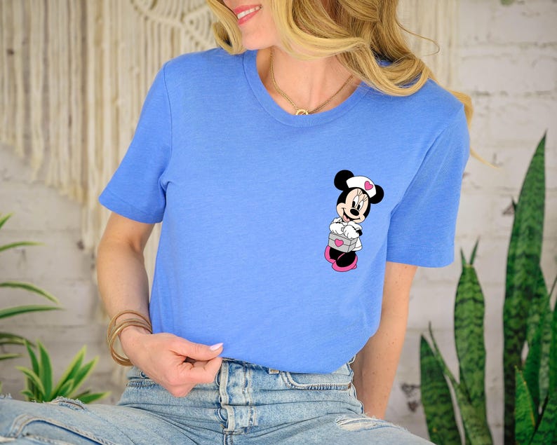 Puede incluir: Camiseta azul claro con un dise&ntilde;o de dibujos animados de Minnie Mouse. El gr&aacute;fico de Minnie Mouse es en negro, blanco, rosa y gris. La camiseta tiene mangas cortas y cuello redondo.