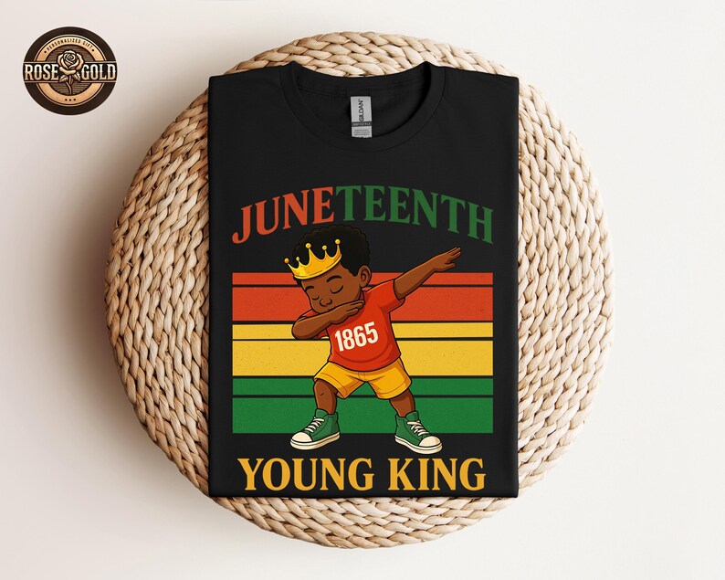 Puede incluir: Camiseta negra con un gr&aacute;fico colorido que celebra el Juneteenth. El dise&ntilde;o presenta una ilustraci&oacute;n de dibujos animados de un joven haciendo un dab, con una corona y el texto "Juneteenth Young King 1865". La camiseta se muestra sobre una superficie tejida.