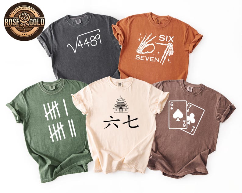 May include: Five different colored t-shirts with various graphic designs. The shirts are in shades of gray, orange, green, beige, and brown. Designs include a math equation, a skeleton hand, tally marks, a pagoda with Chinese characters, and playing cards.