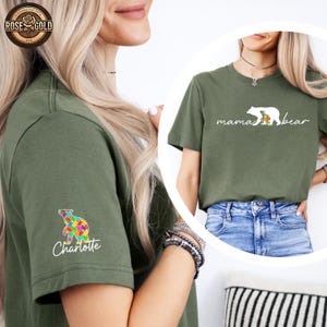 May include: Two green t-shirts with a white bear graphic. The shirt on the left has a colorful puzzle piece bear graphic on the sleeve with the name "Charlotte" underneath. The shirt on the right has the text "mama bear" underneath the bear graphic.