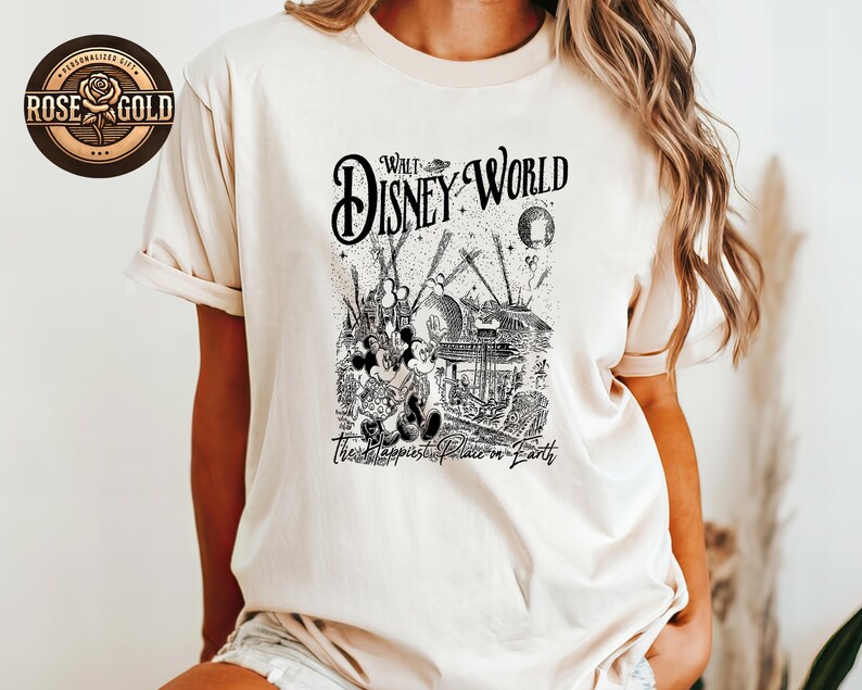 May include: A cream-coloured t-shirt with a black and white graphic of Mickey and Minnie Mouse at Walt Disney World. The design includes the words "Walt Disney World" and "The Happiest Place on Earth."