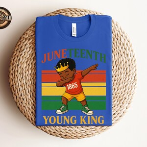Puede incluir: Camiseta azul real con un gr&aacute;fico de un joven negro haciendo un dab, con una corona y el texto "Juneteenth Young King 1865". El dise&ntilde;o presenta rayas rojas, naranjas, amarillas y verdes.