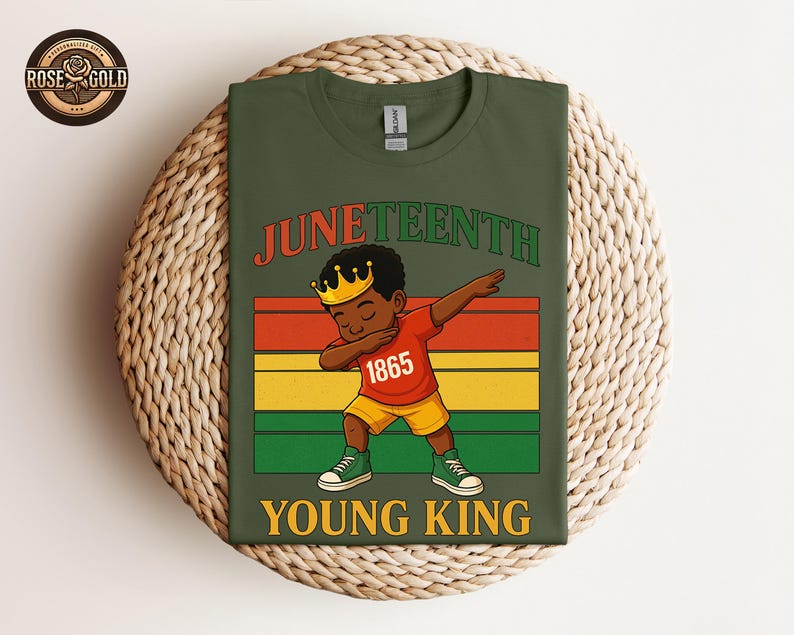 Puede incluir: Camiseta verde oliva con la palabra "Juneteenth" en rojo y verde. La camiseta muestra una ilustraci&oacute;n de dibujos animados de un joven negro haciendo un dab, con una corona y el n&uacute;mero "1865" en su camisa. Las palabras "Young King" est&aacute;n debajo.