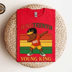 Puede incluir: Camiseta roja con un gr&aacute;fico de un joven negro haciendo dab, con una corona y el n&uacute;mero 1865. Las palabras "Juneteenth" y "Young King" est&aacute;n en verde y amarillo. El dise&ntilde;o incluye rayas rojas, naranjas, amarillas, verdes y negras.