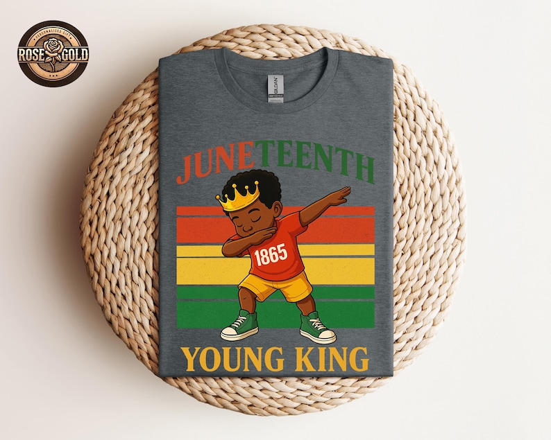 Puede incluir: Camiseta gris oscuro con una ilustraci&oacute;n de dibujos animados de un joven negro haciendo dab, con una corona, una camisa roja con "1865" y pantalones cortos amarillos. La camiseta tiene las palabras "Juneteenth" y "Young King" en naranja y verde.