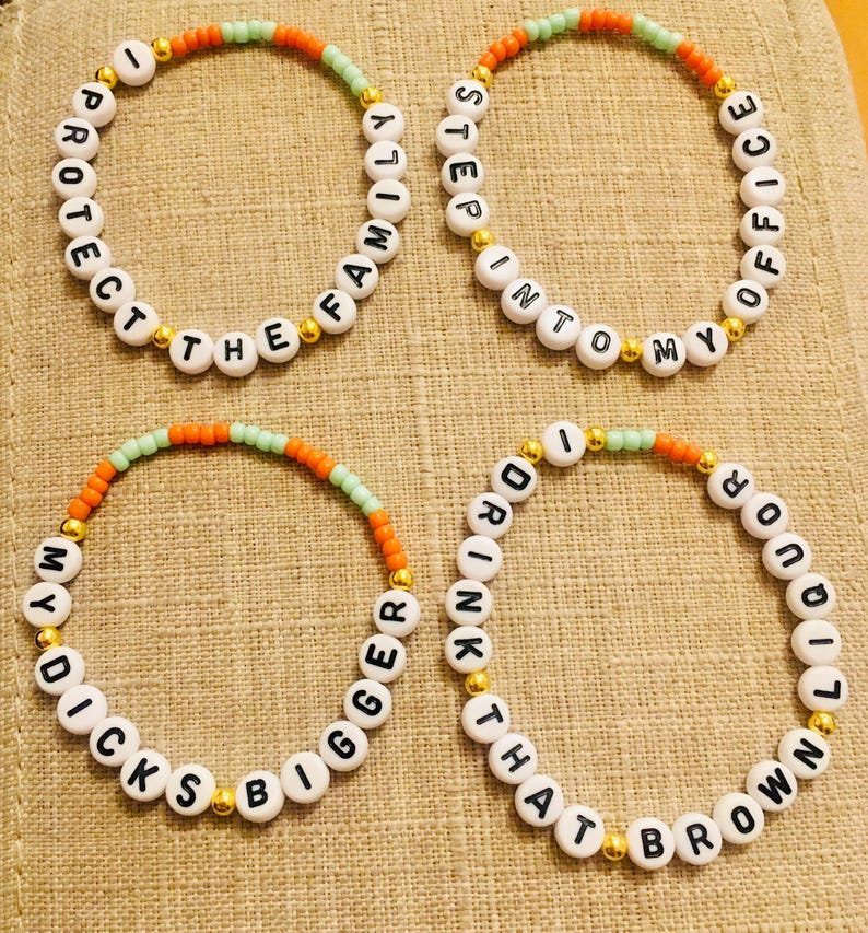 May include: Four beaded bracelets with white letter beads spelling out phrases. The bracelets have orange, green, and gold accents. The phrases include "PROTECT THE FAMILY", "STEP INTO MY OFFICE", "DICKS BIGGER", and "DRINK THAT BROWN LIQUOR".