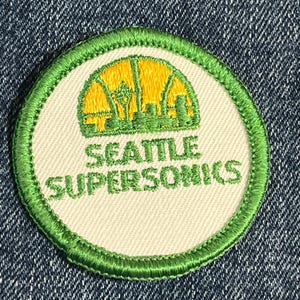 May include: A green and white embroidered patch with a yellow basketball and the words "Seattle SuperSonics".