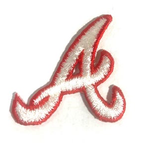 May include: Embroidered patch in the shape of the letter "A". The letter is white with a red border. The patch is likely for a sports team or organization.
