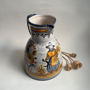 May include: A white ceramic mug with a black handle and the text "But First, Coffee" in a black, handwritten-style font. The mug is on a white surface.