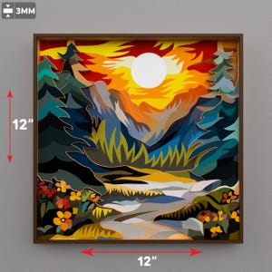 Op de afbeelding: Een 30 cm x 30 cm gelaagd papieren kunstwerk dat een berglandschap bij zonsondergang uitbeeldt. Het kunstwerk gebruikt een levendig kleurenpalet van oranje, geel, blauw en groen, met een bruine lijst. Het bevat een rivier, bomen en een grote zon.