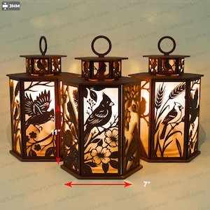 Peut inclure: Trois lanternes hexagonales en bois brun avec des motifs découpés au laser représentant des cardinaux sur des branches avec des fleurs et du blé. Chaque lanterne a une poignée circulaire, mesure 11 pouces de haut et 7 pouces de large.