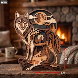 Op de afbeelding: Een meerlaags houten wandkunstwerk met een wolfssilhouet en gedetailleerde uitsparingen van een bos, maan en huilende wolven. Het object is 30,48 cm hoog en 24,13 cm breed en is opgebouwd uit houten lagen van 3 mm dik.