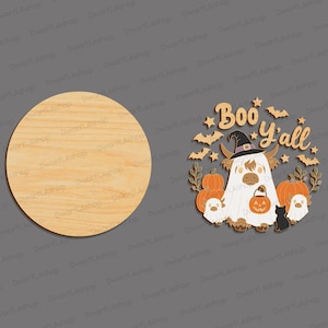 May include: A circular light-coloured wooden plaque next to a decorative wooden cutout featuring a highland cow wearing a ghost sheet and witch hat, surrounded by pumpkins, bats, stars, and the text Boo Y'all, with two small ghost figures.