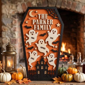 May include: A coffin-shaped wooden sign with an orange background, black border, and a black haunted house silhouette at the bottom. It features a crescent moon, stars, spiderwebs, bats, and five ghost cutouts labelled Mom, Dad, Sophia, Anna, and Noah.