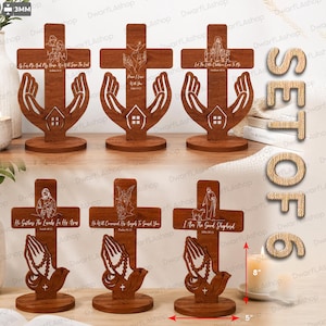 May include: A set of six brown wooden crosses, each 8 inches tall and 5 inches wide, featuring laser-engraved religious imagery and text. The designs include praying hands, a house cutout, and various biblical figures with scripture verses.