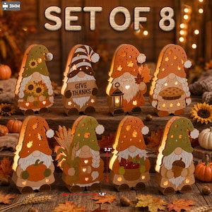 Peut inclure: Un ensemble de 8 décorations en bois en forme de gnome sur le thème de l'automne, avec tournesols, citrouilles, pommes et un panneau GIVE THANKS. Chaque gnome présente des découpes en forme d'étoiles et de cœurs lumineuses. Dimensions 8,1 cm par 4,6 cm.