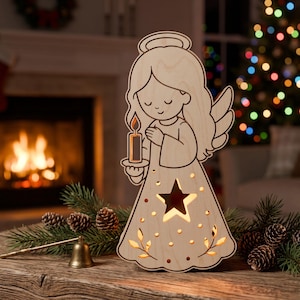 May include: A light-colored wooden angel cutout featuring a halo, long hair, and closed eyes. The angel holds a lit candle, and the dress is decorated with a star-shaped cutout and small leaf patterns that emit a warm, glowing light from within.