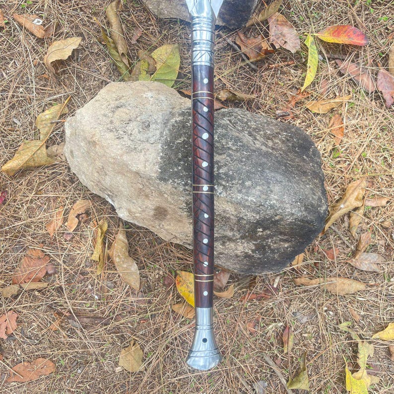 May include: A wooden-handled spear with a silver metal tip and decorative accents. The handle is wrapped in brown leather with silver metal accents.