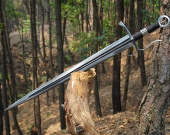 May include: A silver sword with a black leather grip and a silver pommel. The sword is resting on a wooden log in a forest setting.