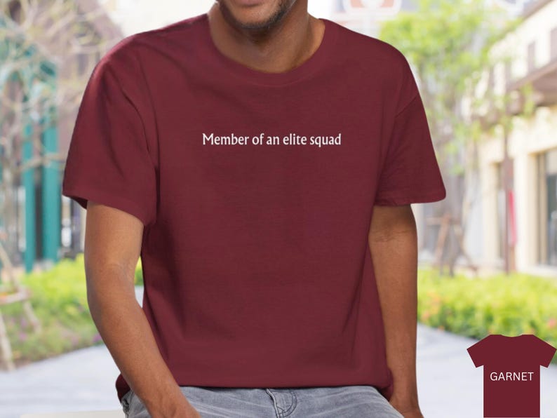May include: A maroon t-shirt with white text that reads "Member of an elite squad".