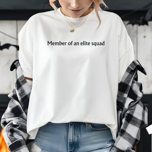 May include: White long-sleeve shirt with the text "Member of an elite squad" printed on the front.