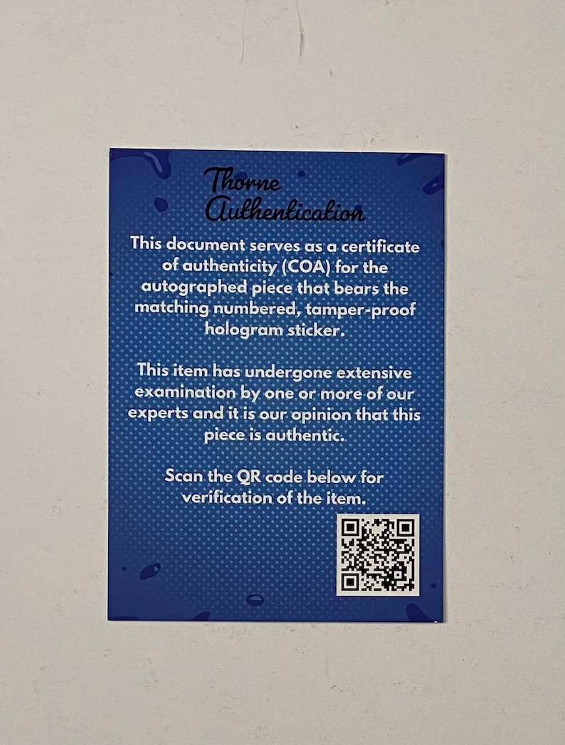 May include: A blue certificate of authenticity with the text "Thorne Authentication." The document states it serves as a COA for an autographed item with a matching hologram sticker. It also includes a QR code for verification.