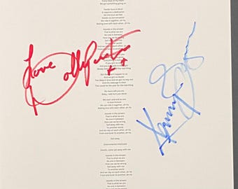 May include: A white paper sheet featuring printed song lyrics in black text, including the lines Islands in the stream and Sail away with me. The document is signed with a red ink signature on the left and a blue ink signature on the right.