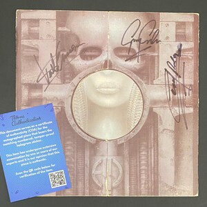 May include: A signed album cover featuring a surreal, biomechanical artwork in shades of brown and beige. The cover has multiple signatures and a blue Thorne Authentication certificate with a QR code.