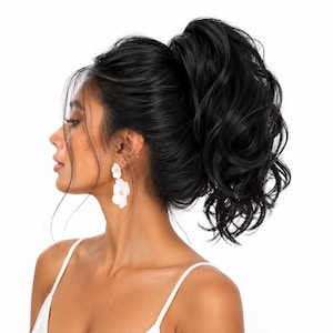 May include: A high ponytail hair extension in a deep black shade featuring voluminous, wavy texture. The hair is styled in a full, elevated ponytail with loose strands framing the face. The piece is designed to be attached to natural hair.