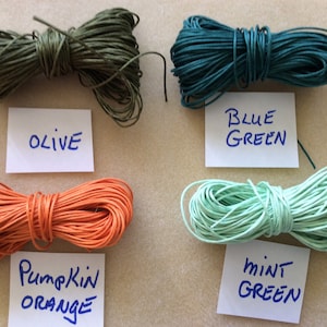 May include: Five spools of waxed cotton cord in different colors: olive green, blue green, pumpkin orange, mint green, and brown. The spools are labeled with their colors.