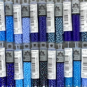 May include: A collection of 16 small glass bead containers, each with a different color and finish. The beads are all round and are labeled with the brand "TOHO" and the size "8". The containers are arranged in two rows of eight.