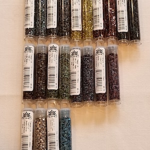 May include: A collection of 16 small tubes of TOHO Triangle 11/0 seed beads in various colors and finishes. The tubes are labeled with the bead size, color, and finish.