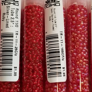 Pode incluir: Tr&ecirc;s tubos de contas de sementes vermelhas e rosadas Toho. Os tubos s&atilde;o etiquetados com o tamanho das contas, a cor e o pre&ccedil;o. As contas s&atilde;o de tamanho 11/0 e t&ecirc;m 2,5 polegadas de comprimento. O pre&ccedil;o &eacute; de $ 1,95 por tubo.