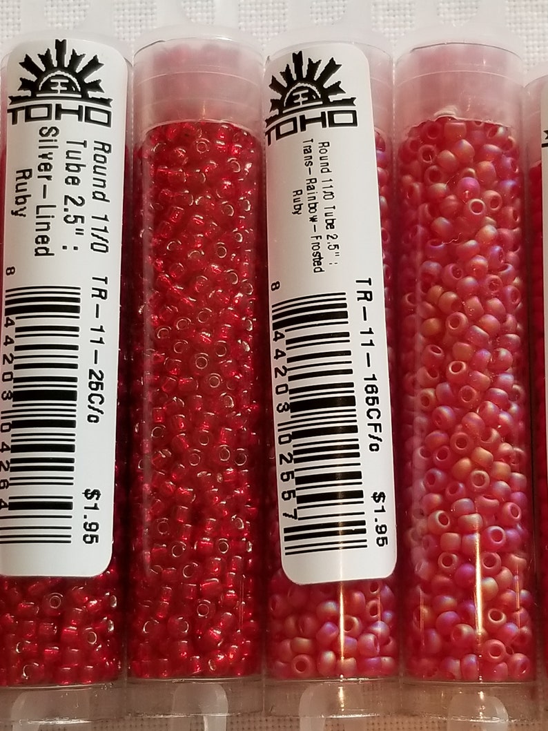 Pode incluir: Tr&ecirc;s tubos de contas de sementes vermelhas e rosadas Toho. Os tubos s&atilde;o etiquetados com o tamanho das contas, a cor e o pre&ccedil;o. As contas s&atilde;o de tamanho 11/0 e t&ecirc;m 2,5 polegadas de comprimento. O pre&ccedil;o &eacute; de $ 1,95 por tubo.