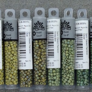 May include: Six small tubes of TOHO brand size 8 round semi-glazed rainbow beads in the colors lemongrass, olive, honeydew, clover, and two more shades of green.