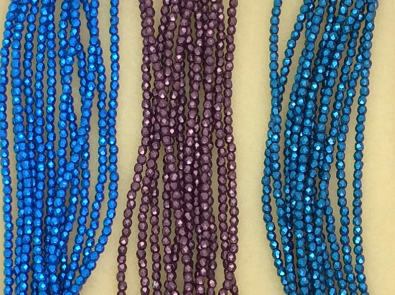 May include: Three strands of faceted metallic beads. One strand is blue, one is purple, and one is teal.