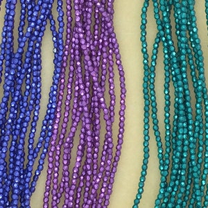 May include: Three strands of faceted glass beads in blue, purple, and teal colors. The beads are small and have a metallic sheen.