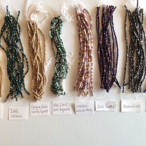 May include: Assortment of glass beads in various colors and finishes, including matte metallic flax, iris green, opaque gold smoky topaz, blue jeans/porte vinagasse, opaque luster mix, iris purple, hematite, and iris blue.
