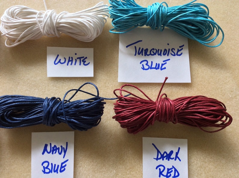 May include: Four spools of waxed cotton cord in white, turquoise blue, navy blue, and dark red. Each spool is labeled with the color name.